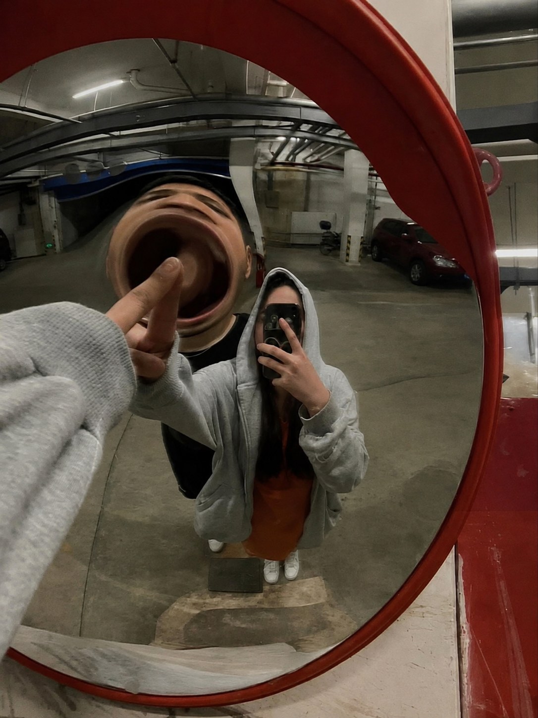 A friend photographing themselves in a convex traffic mirror